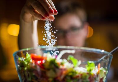 Persona salando una ensalada.