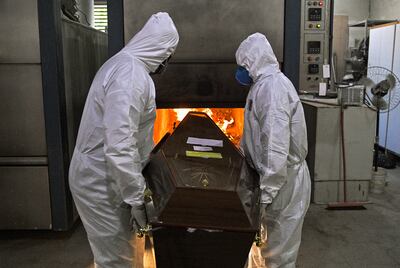 Trabajadores de un crematorio ataviados con trajes de protección como una medida de prevención contra el coronavirus, meten un féretro en el horno del cementerio Sao Francisco Xavier en Río de Janeiro, Brasil.