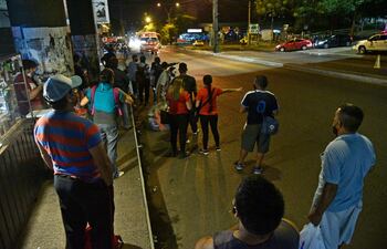 Pasajeros esperan colectivo en los alrededores de la Terminal de Ómnibus de Asunción, para retornar al hogar, durante una noche de regulada del transporte público.