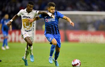 El paraguayo Ángel Romero (d), del Cruz Azul, intenta zafarse de la marca del ecuatoriano Washington Corozo, de Pumas, durante el partido que empataron sin goles.