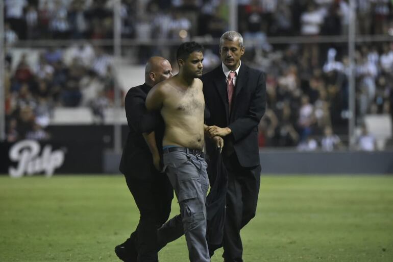 El hincha de Guaraní que ingresó al campo es sujetado y retirado por la seguridad privada de La Huerta.