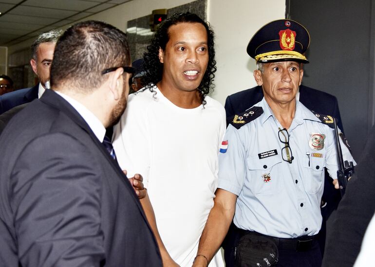 Bajo custodia de policías y guardias de civil del Poder Judicial, Ronaldinho sale del ascensor de magistrados para ser conducido hasta el juzgado penal de garantías. Fue a la siesta.