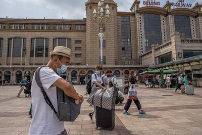 Personas con mascarillas protectoras caminan hacia la estación de tren de Beijing en medio de la pandemia de coronavirus en Beijing, China, el 9 de agosto de 2021.