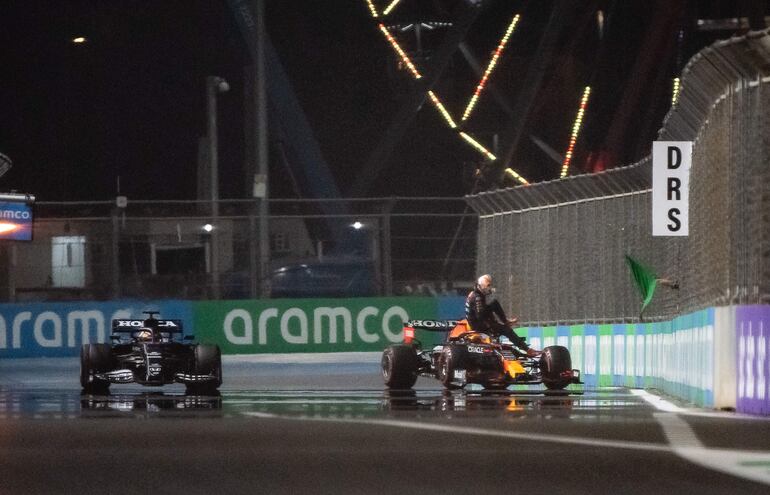 El inglés Lewis Hamilton (Mercedes, izquierda), acaba de confirmar la "pole" para el GP de Arabia Saudí, mientras el holandés Max Verstappen desciende de su Red Bull tras chocar por la barrera de protección en su vuelta rápida.