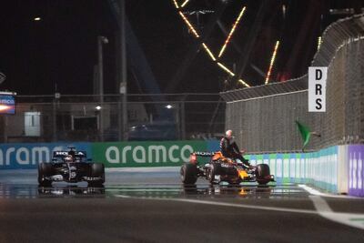 El inglés Lewis Hamilton (Mercedes, izquierda), acaba de confirmar la "pole" para el GP de Arabia Saudí, mientras el holandés Max Verstappen desciende de su Red Bull tras chocar por la barrera de protección en su vuelta rápida.