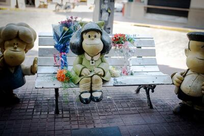 En Buenos Aires, ramos de flores acompañan la estatua ubicada frente a la exvivienda de Quino.