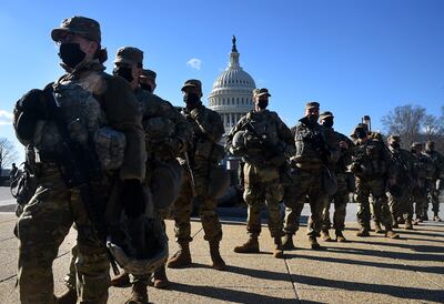 Los miembros de la Guardia Nacional se reúnen en un puesto de control de seguridad cerca del Capitolio de los Estados Unidos, antes de la 59a ceremonia inaugural del presidente electo Joe Biden y la vicepresidenta electa Kamala Harris en Washington, DC el 19 de enero de 2021.