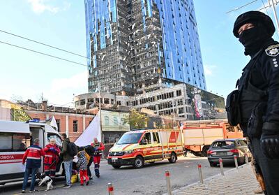 Un policía ucraniano y trabajadores médicos cerca de un edificio parcialmente destruido en Kiev, este lunes.