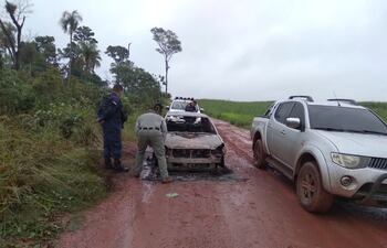 Policías revisan el automóvil que fue quemado con dos cuerpos adentro.