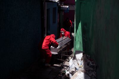 Trabajadores funerarios vestidos con trajes de bioseguridad llevan el cuerpo de un hombre de 75 años que murió, presuntamente víctima de COVID-19, en El Salvador,