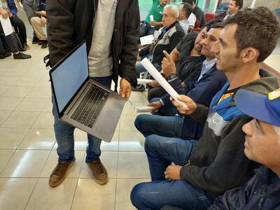 Los choferes de las diversas empresas de transporte pública observan una computadora con los detalles de la aplicación.