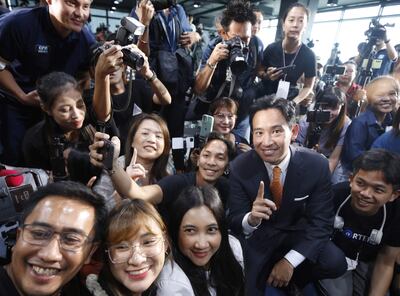 Pita Limjaroenrat, en el centro, con corbata anaranjada, posa con periodistas durante una conferencia.