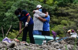 Dos hombres lloran durante el entierro de una víctima de COVID-19 en un anexo del cementerio Parque Memorial Jardín de Los Ángeles, en Honduras.
