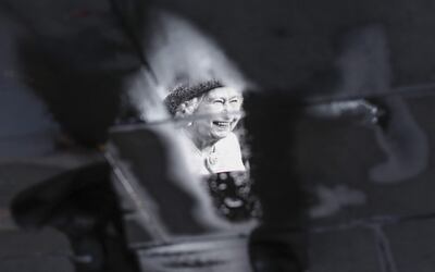 Vista de la imagen de Isabel II reflejada en un charco en Piccadilly Circus en Londres, Reino Unido.
