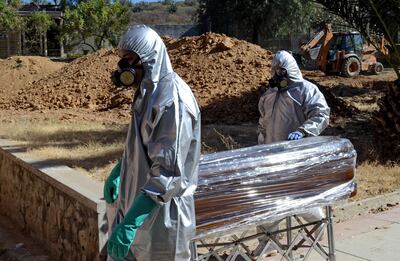 Trabajadores transportan el ataúd de una persona que falleció a causa de COVID-19, en un cementerio de Cochabamba, Bolivia.