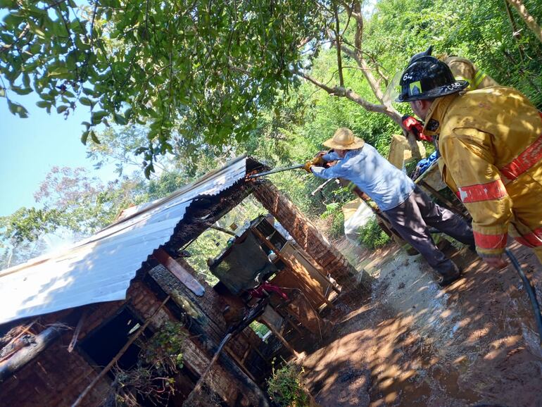 Momento en que un vecino colabora con los bomberos para que el fuego no continúe en la paja bajo la chapa