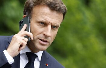 El presidente de Francia, Emmanuel Macron habla por su teléfono celular desde el castillo Elmau, en Alemania.