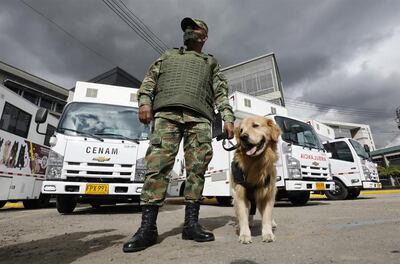 Un soldado y su perro detector de explosivos junto a las ambulancias donadas por el empresario Howard Buffett, este miércoles en Bogotá (Colombia).