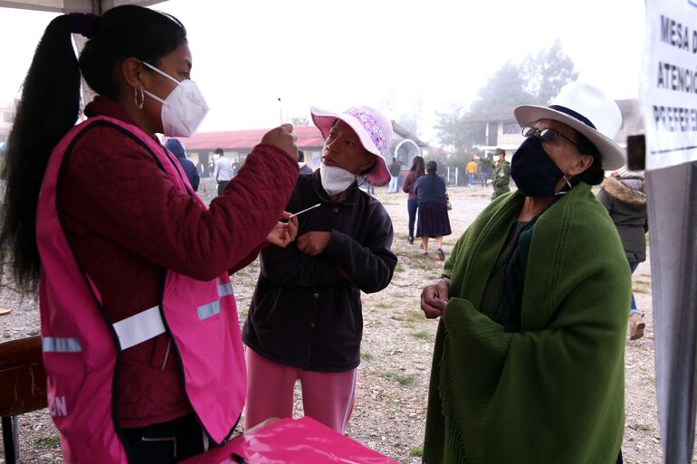 Una voluntaria asiste a una votante en un puesto electoral en una parroquia en Cuenca, Ecuador.