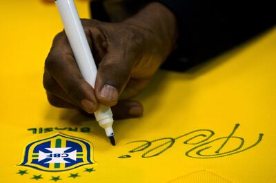 (FILES) In this file photo taken on June 10, 2013, Brazilian football legend Edson Arantes do Nascimento, known as Pele, signs a Brazilian national team shirt during a press conference at Volkswagen plant in Sao Bernardo do Campo, in the metropolitan area of Sao Paulo, Brazil. - "Pele," arguably the best footballer in history, is now also an adjective. On April 26, 2023, "pele" was added to the more than 167,000 words in the Michaelis Portuguese dictionary printed in Brazil. (Photo by Nelson ALMEIDA / AFP)
