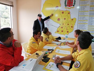 El jefe de los bomberos, Rafael Valdez, muestra en el mapa la zona más afectada por los incendios, durante una reunión con bomberos forestales.