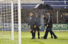 El árbitro Carlos Paul Benítez encabeza junto a sus colaboradores el recorrido por la mojada –y sin pintura– cancha del 12 de Octubre,