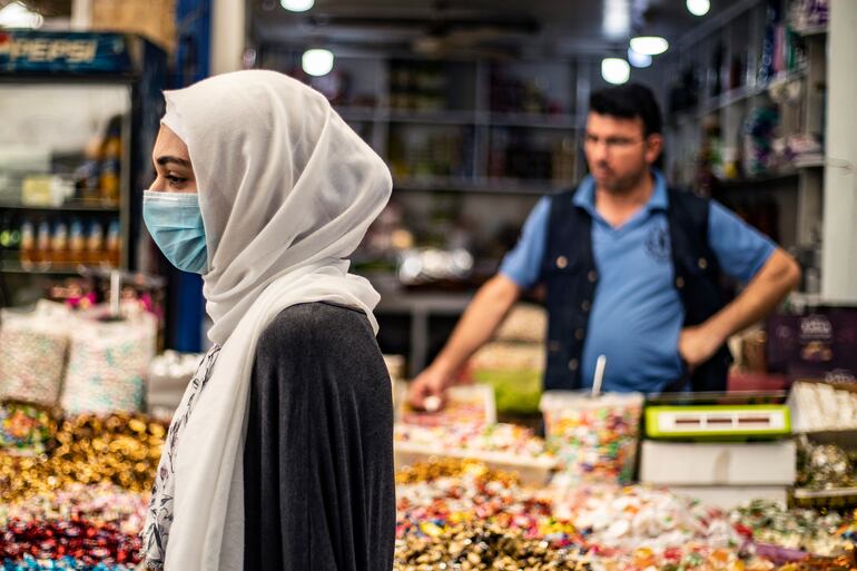 Una mujer con mascarilla camina en un mercado en la ciudad de Qamishli, Siria.