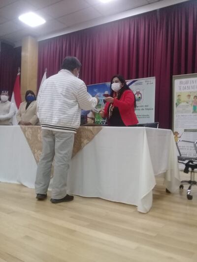 Mirta Montiel, de la Cámara de comercio de Encarnación, entrega el crédito a uno de los beneficiarios.