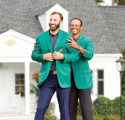 Emotivo momento, Tiger Woods, ganador del año pasado, enfunda la chaqueta verde a Dustin Johnson. (EFE).