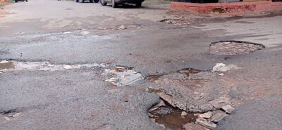 Baches, asfaltado con grietas y agua en la calle