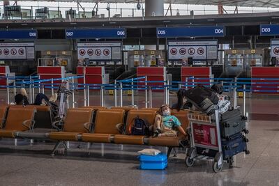 Un niño con tapabocas y un visor reposa junto a sus maletas en la terminal 3 del Aeropuerto Internacional de Pekín, casi vacío.