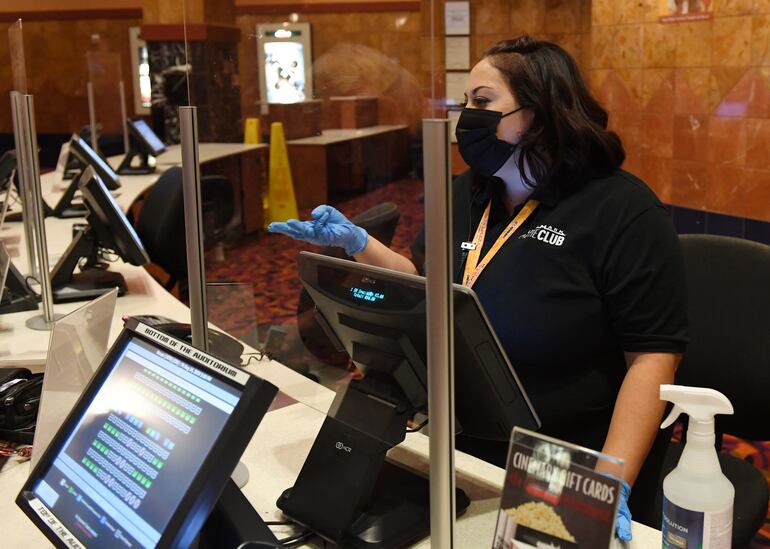 Sarah Ochoa, trabajadora en un cine en Estados Unidos, se ubica detrás de un escudo de plexiglass, con tapabocas y guantes.
