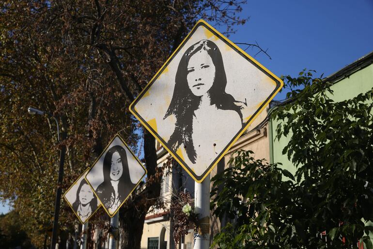 Tres señales de tránsito con los rostros de las uruguayas Laura Raggio (al frente), Diana Maidanik (primera atrás) y Silvia Reyes marcan la esquina del sitio donde fueron asesinadas, en el barrio Brazo Oriental, en Montevideo (Uruguay), el 19 de mayo de 2022.
