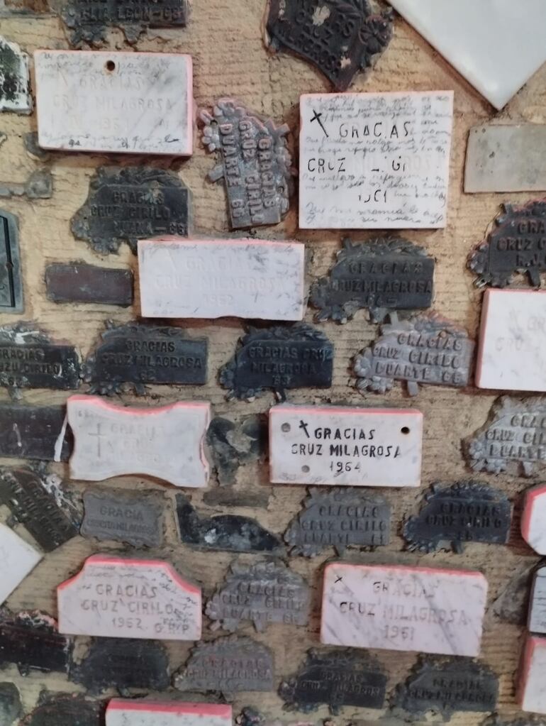 Placas de diferentes materiales, con agradecimiento de los fieles, adornan el espacio.