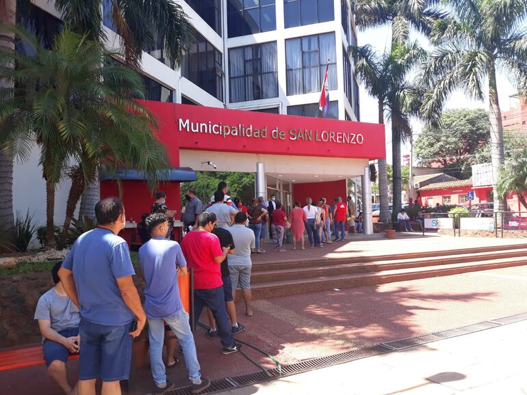 Algunos contribuyentes aprovecharon parte de la sombra que da el edificio municipal para formar la fila y protegerse del intenso calor.