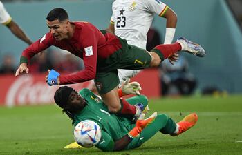 Cristiano Ronaldo choca con el arquero ghanés Lawrence Ati Zigi, durante el partido de ayer.