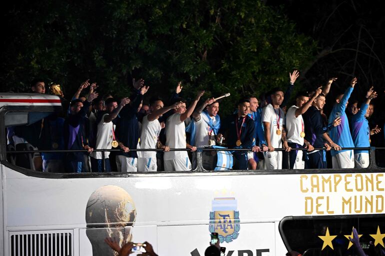 Los jugadores de la selección de Argentina a bordo del bus descapotable durante el recorrido hasta el predio de Ezeiza en compañía de miles y miles de argentinos, que recibieron al plantel en el Aeropuerto Internacional de Ezeiza después de la conquista del Mundial Qatar 2022. 