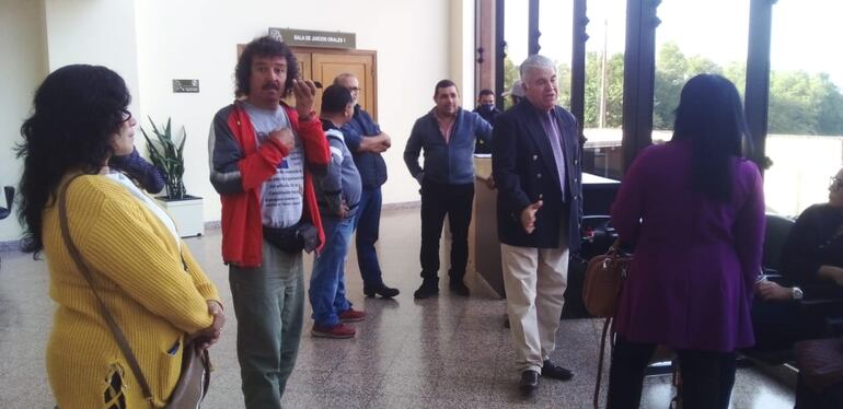 Oscar Flecha, en el centro, al fondo, compareció al Palacio de Justicia esta mañana, acompañado de unos miembros de la organización Ciudadanos Unidos de Itapúa, en la causa por supuesta difamación entablada por el ex gobernador Juan Schmalko, pero no hubo juicio, ni estaba previsto.