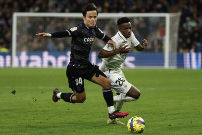 El centrocampista japonés de la Real Sociedad, Takefusa Kubo (i), disputa el balón ante el delantero brasileño del Real Madrid, Vinicius Jr., durante el encuentro correspondiente a la jornada 19 de primera división que disputaron ayer en el estadio Santiago Bernabéu, en Madrid. EFE / Juanjo Martín.