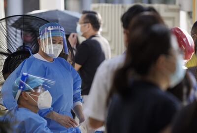 Un trabajador médico observa a las personas que esperan en fila para la prueba de PCR de Coronavirus en una cabina de pruebas en la calle, en Shanghái, China.