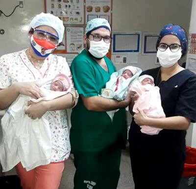 Personal de salud del Hospital General de Luque posa con las tres pequeñas nacidas el viernes.