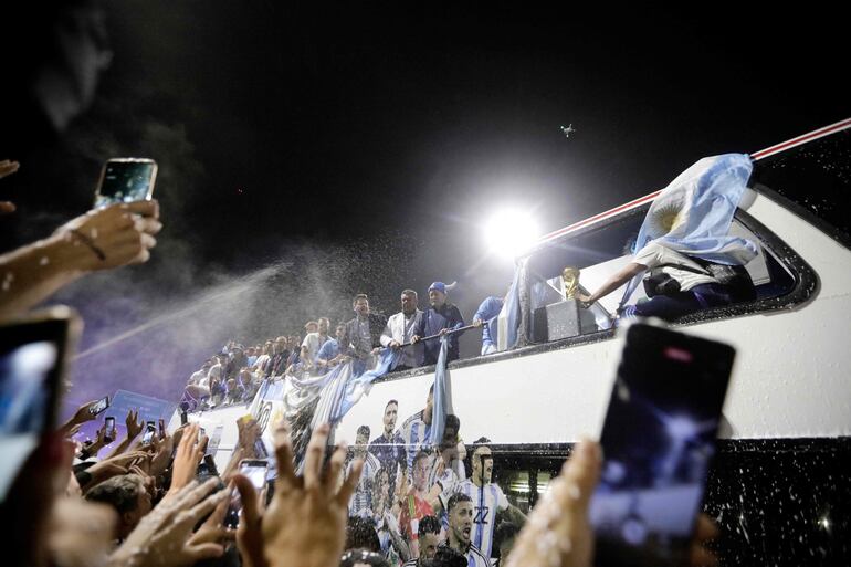 Los jugadores de la selección de Argentina a bordo del bus descapotable durante el recorrido hasta el predio de Ezeiza en compañía de miles y miles de argentinos, que recibieron al plantel en el Aeropuerto Internacional de Ezeiza después de la conquista del Mundial Qatar 2022. 