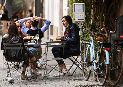 Un grupo de personas toma tragos en una terraza al aire libre en el centro de Roma.