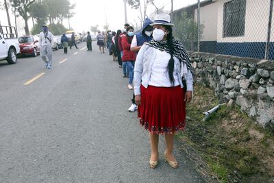 Personas con mascarillas hacen fila para votar en un puesto electoral en Cuenca, Ecuador.