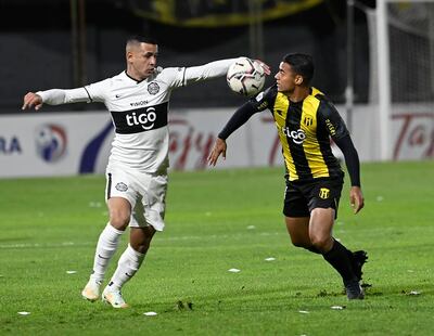 Derlis González extiende los brazos en su intento por controlar el balón, ante la cobertura defensiva de Marcelo Benítez. El “10” franjeado no tuvo una noche inspirada, aunque le puso ganas.