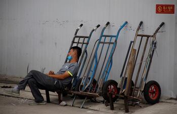 Un trabajador migrante se echa una siesta mientras espera para conseguir un empleo, en Pekín.