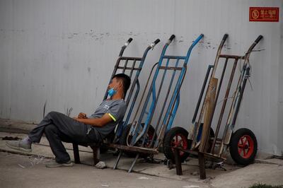 Un trabajador migrante se echa una siesta mientras espera para conseguir un empleo, en Pekín.