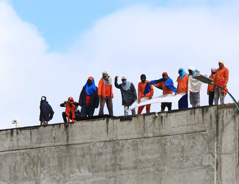 Presos protestan en los techos del centro de privación de la libertad N.1 hoy, en Cuenca (Ecuador). La crisis carcelaria de Ecuador sumó un nuevo trágico episodio en el que fueron asesinados al menos 12 presos, durante enfrentamientos en la prisión de la sureña ciudad de Cuenca, similares a los ya acontecidos el año pasado, que dejaron 316 reclusos fallecidos en peleas entre bandas rivales. 