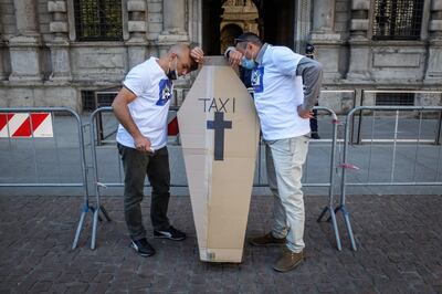Taxistas de la agrupación profesional Assotaxi posan mientras participan en una protesta delante del Palazzo Marino, el ayuntamiento de la localidad, en Milán (Italia) este miércoles, mientras participan en un entierro simulado de la profesión debido a las consecuencias que el COVID-19 han provocado en el sector.