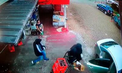 Los maleantes abandonan la distribuidora con el botín cargado en una caja.